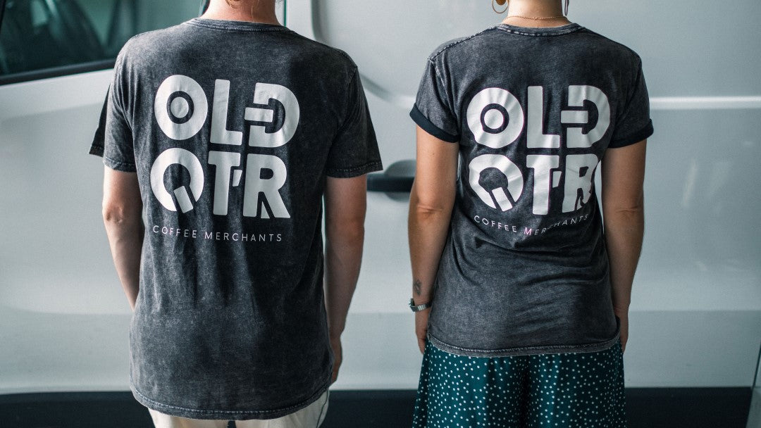 Old Quarter Coffee Merchants - Roasters of the best sustainable, specialty organic, ethical & Direct Trade Specialty Coffee from Southeast Asia, Based in Ballina NSW (Just south of Byron bay). Stonewash, Unisex T-shirt with pocket logo on front and centred logo on back, back view shown on female.